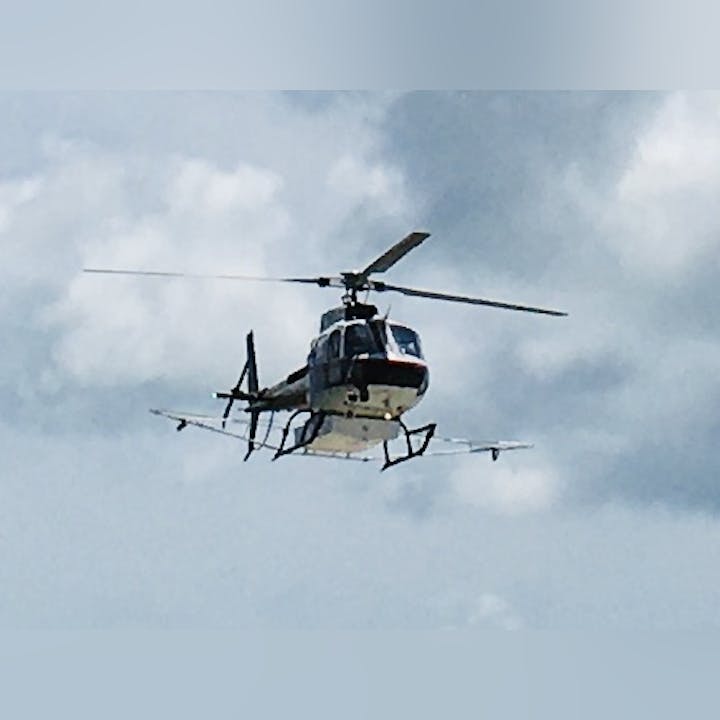 A helicopter flying against a cloudy sky.