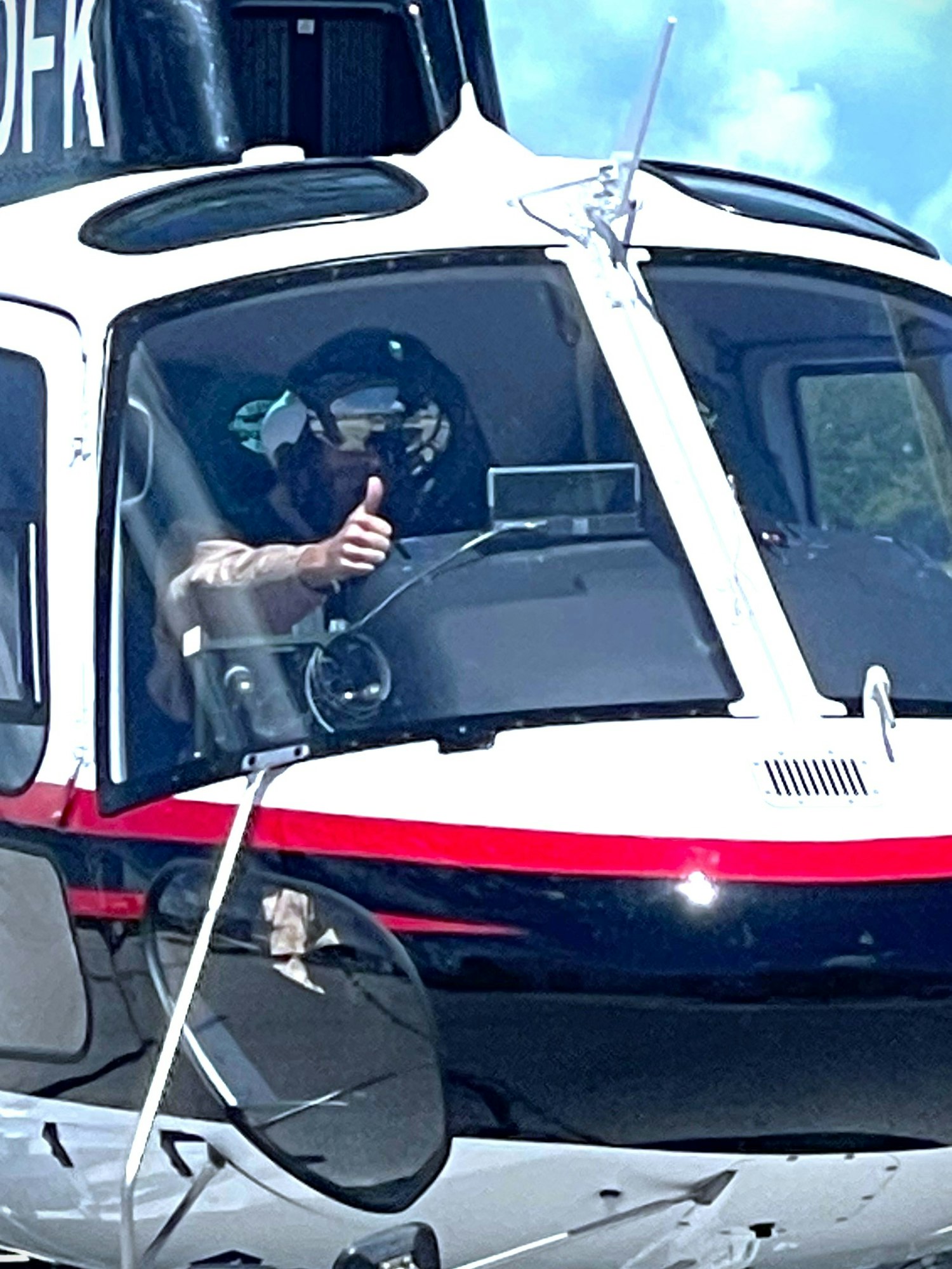 Helicopter cockpit with a pilot giving a thumbs-up.