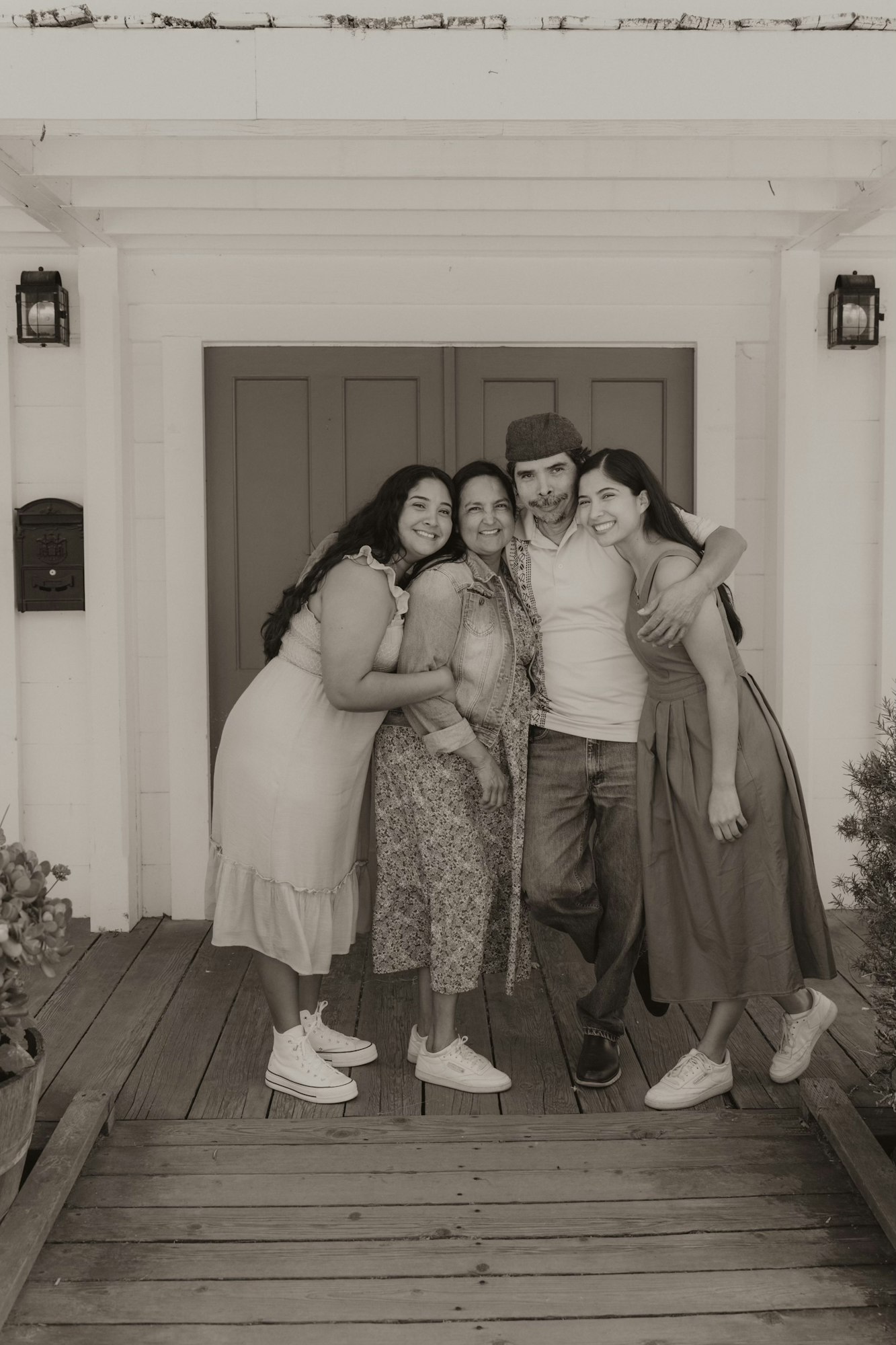 Katia and her family hugging and smiling on a porch, sepia-toned photo.