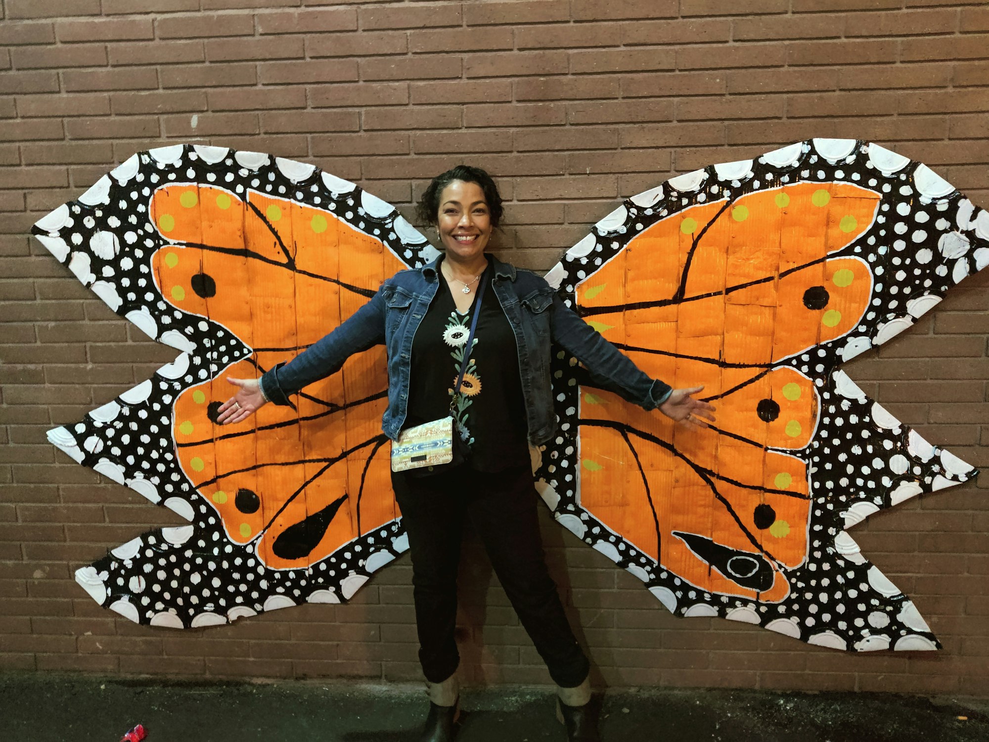 Bianca  posing with wings painted on a wall, resembling a butterfly.