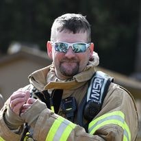 A firefighter in gear with reflective sunglasses.