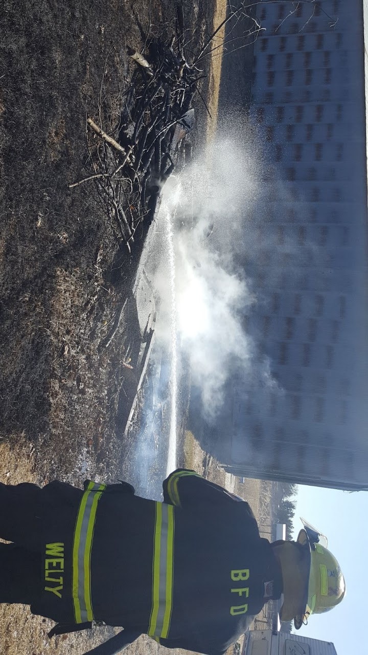 A firefighter spraying water on a small debris fire.