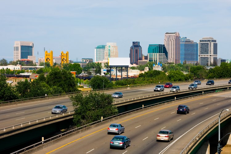 Highway with cars, city skyline in the background, clear sky.