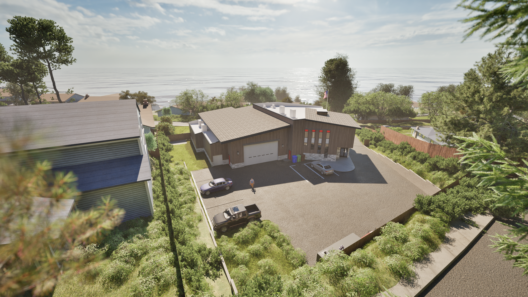 A modern building with cars parked outside, surrounded by green trees and shrubs, overlooking a shoreline in the background.