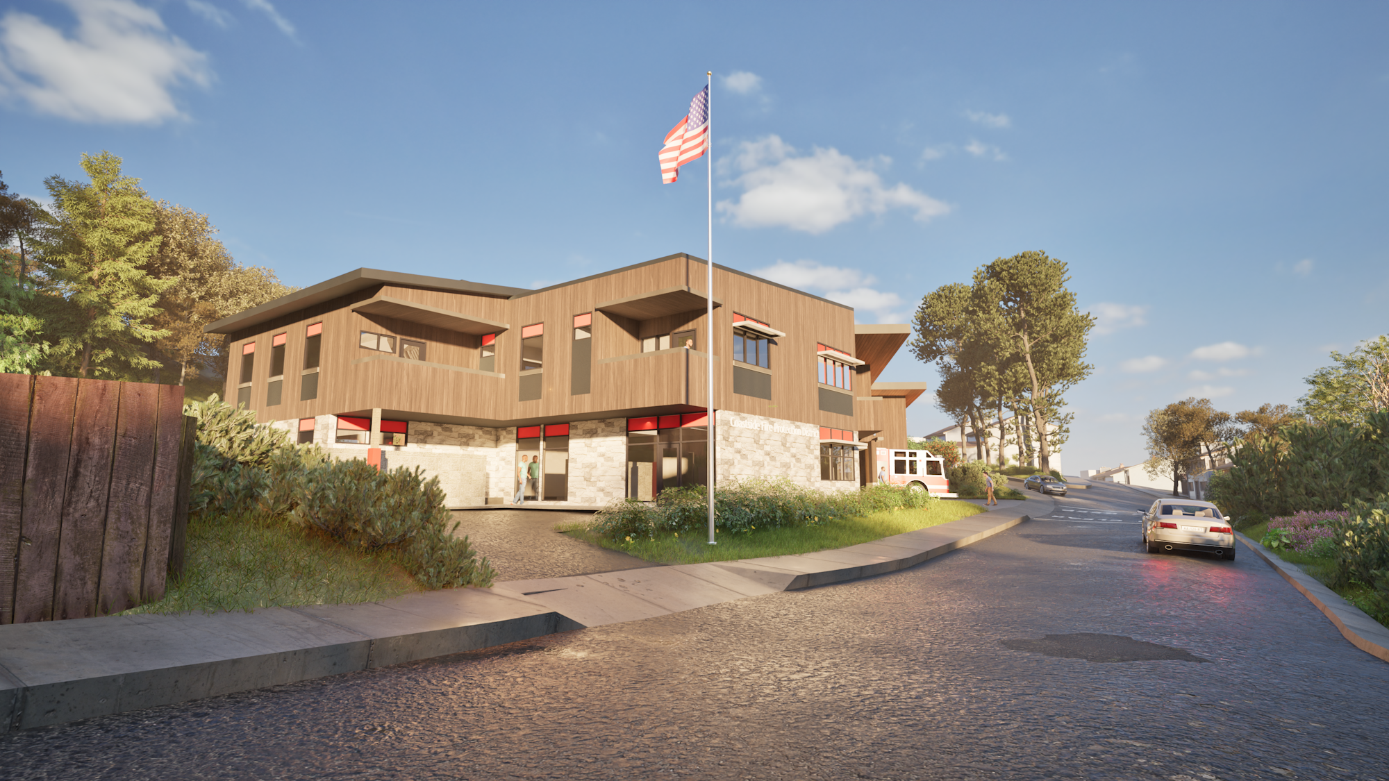 Modern two-story building with a flagpole, surrounded by trees and cars on a paved road.