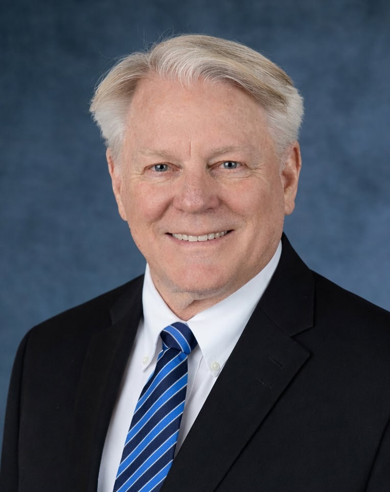 The image features a smiling man in a suit with a blue tie, set against a blue background.