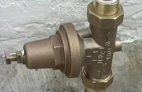 The image shows a brass valve with connectors, likely a pressure regulator or control valve used in plumbing systems.