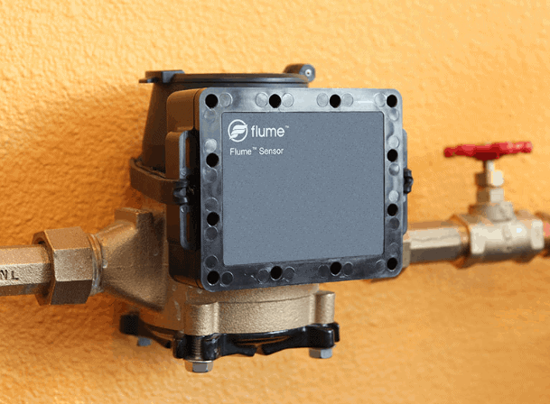 The image shows a Flume water sensor mounted on a pipe, used for monitoring water usage.