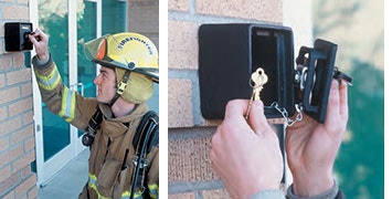 A firefighter is using a key lock box on a wall to access a key inside.