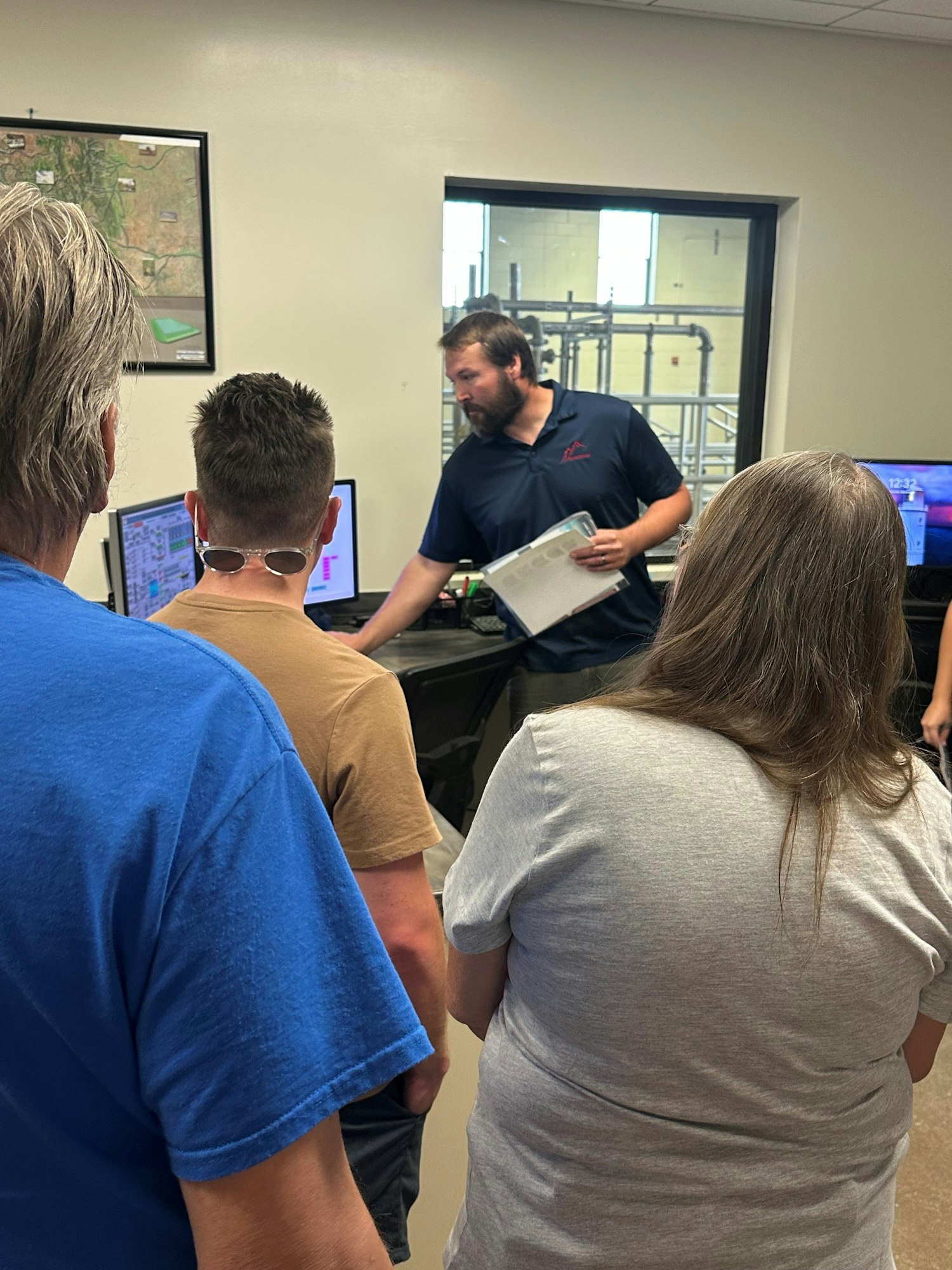 A person is presenting information on computer screens to a group of people in an office setting.