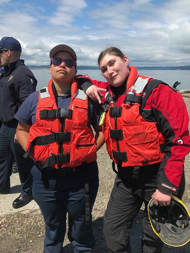 May contain: clothing, lifejacket, vest, person, accessories, glasses, footwear, shoe, coat, jacket, hat, face, head, photography, and portrait
