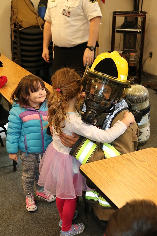 May contain: helmet, face, head, person, photography, portrait, clothing, hardhat, costume, pants, footwear, shoe, child, female, girl, accessories, bag, handbag, people, wood, wristwatch, desk, furniture, and table