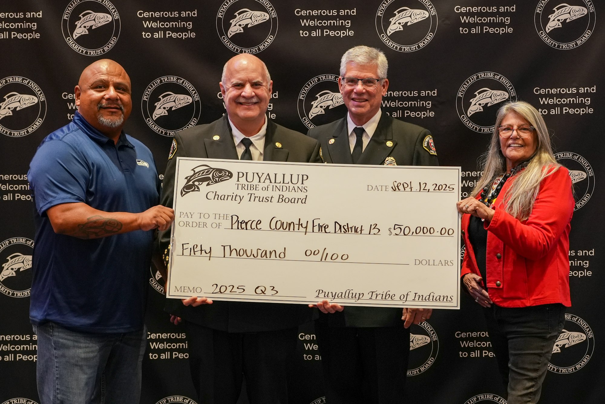 Four people holding a large $50,000 check from Puyallup Tribe of Indians Charity Trust to Pierce County Fire District 13.