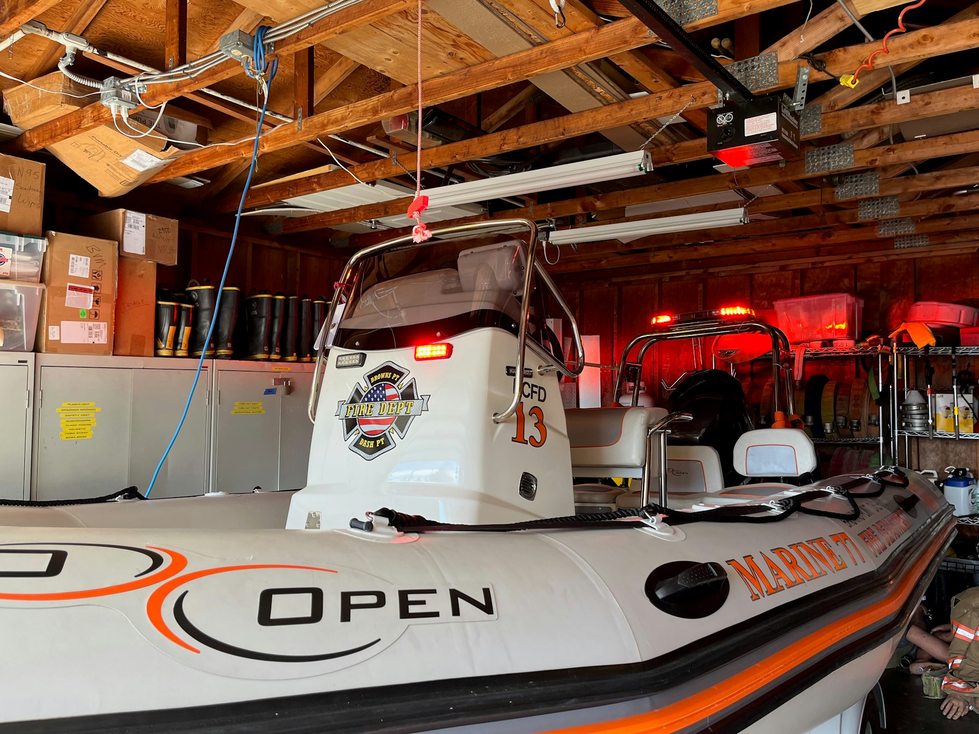 Fired department rescue boat stored on a trailer and parked inside garage.