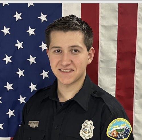 A person in a uniform in front of an American flag.