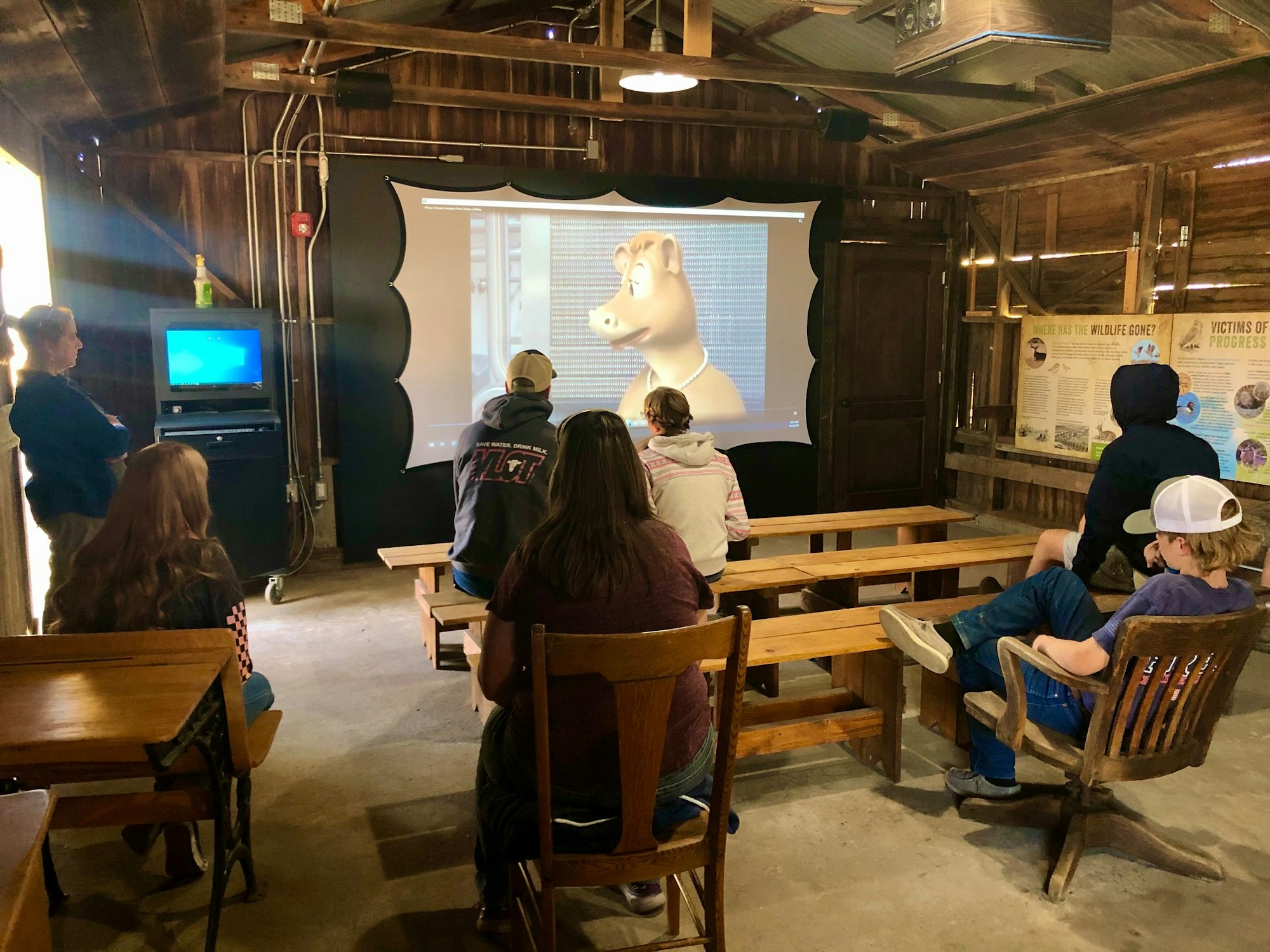 May contain: person, human, screen, electronics, projection screen, wood, sitting, chair, furniture, monitor, and display