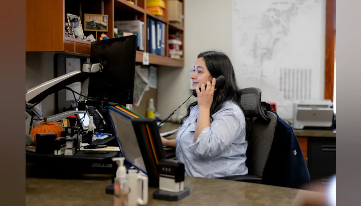 A woman is talking on the phone in an office setting.