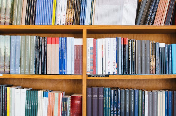 Wooden bookshelves filled with assorted books and journals at Uppsala University.