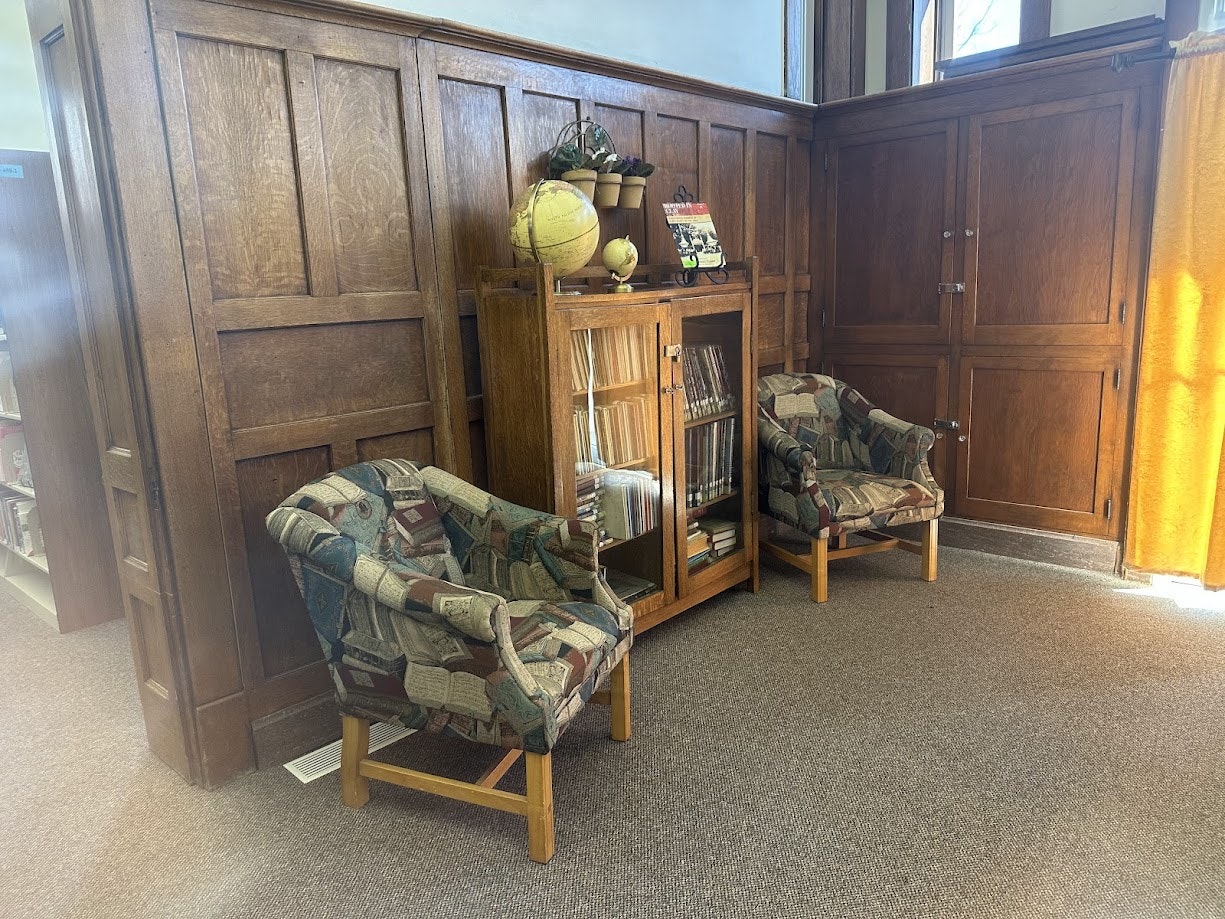 Cozy room with two patterned chairs, a wooden cabinet filled with books, and a globe on top.