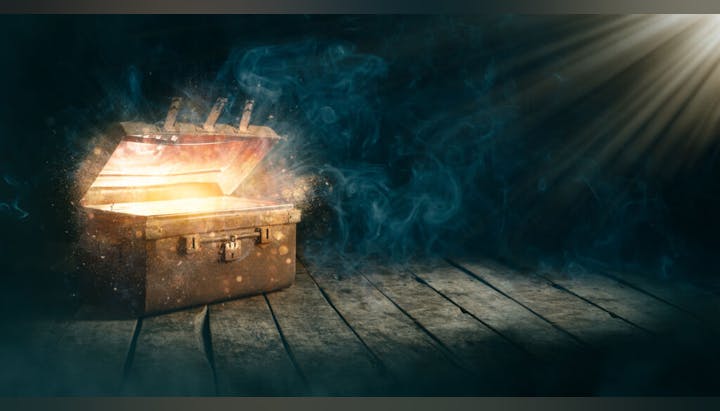 An open chest emitting a bright, magical glow with beams of light and smoke on a wooden floor.