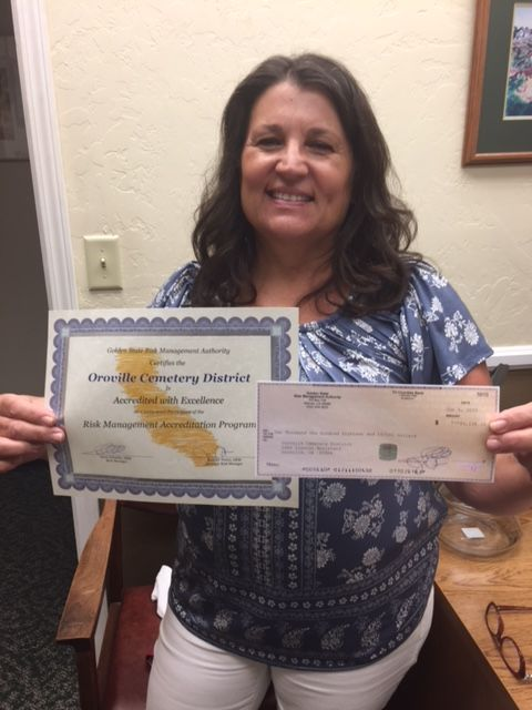 A person is holding a certificate for Oroville Cemetery District and a check.
