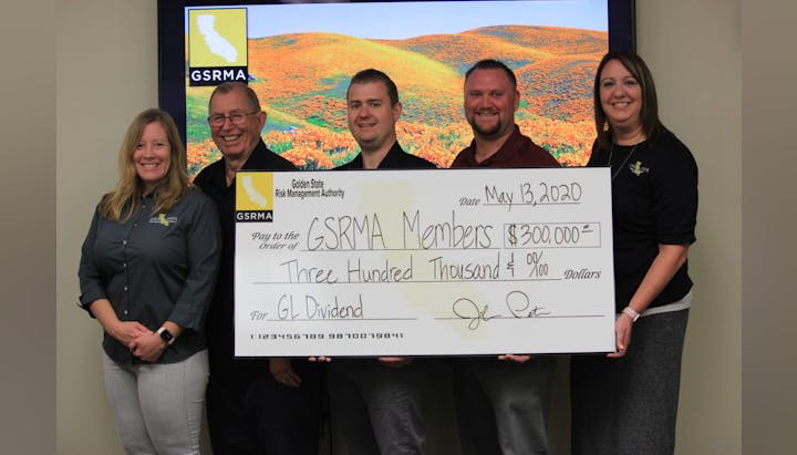 Five people holding a large check from GSRMA for $300,000 to GSRMA Members dated May 13, 2020, for GL Dividend.