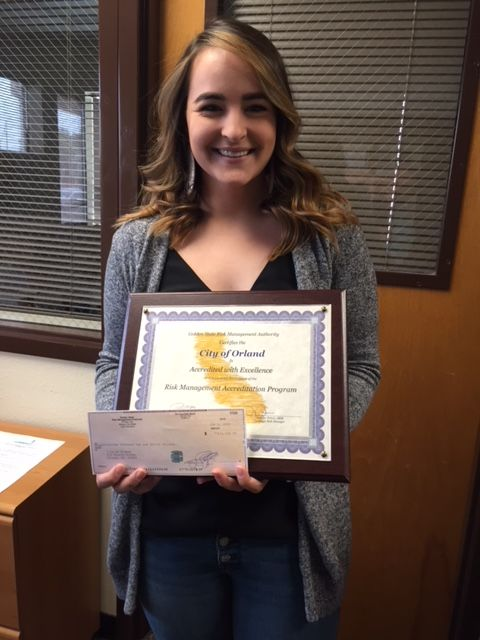 A person holding a framed certificate and a check in an office.