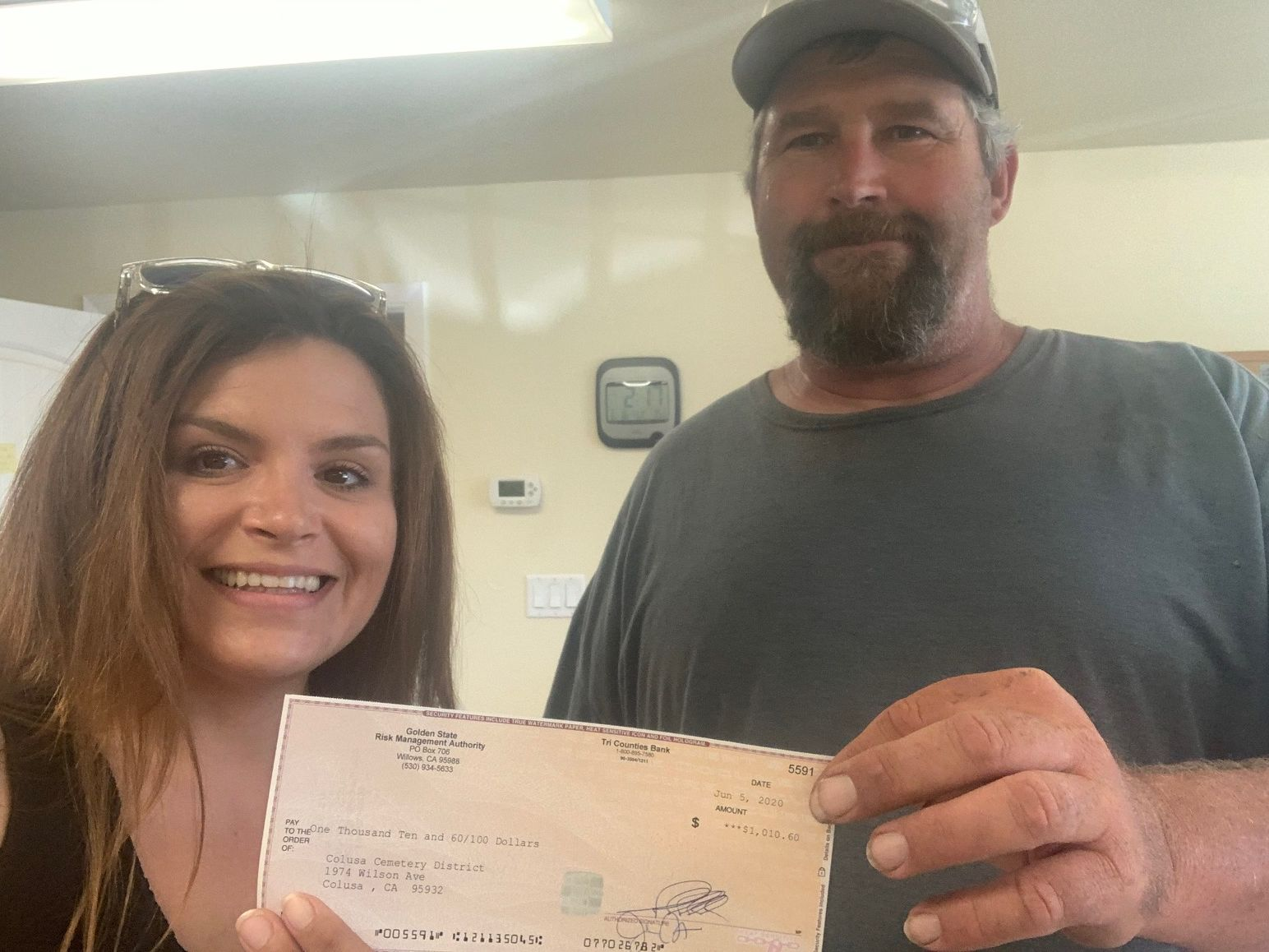 Two people smiling and holding a check for $1,010.60.