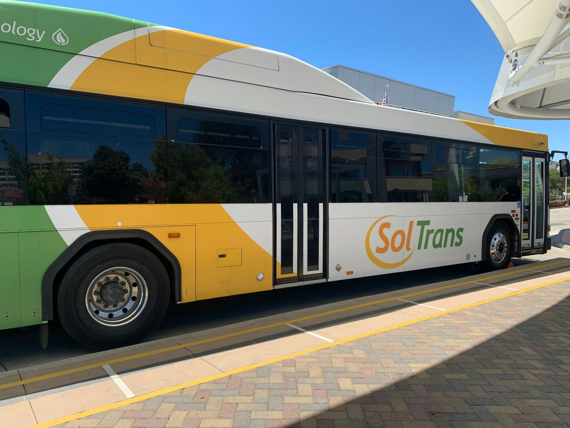 A SolTrans bus at a station, with a green, white, and yellow design.