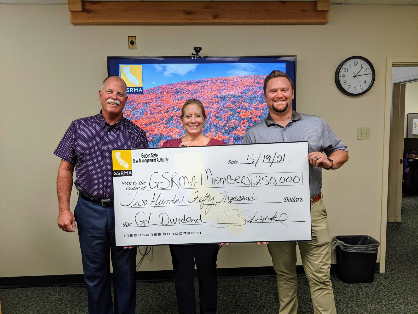 Three people holding a large check for $250,000 from Golden State Risk Management Authority dated 5/19/21.
