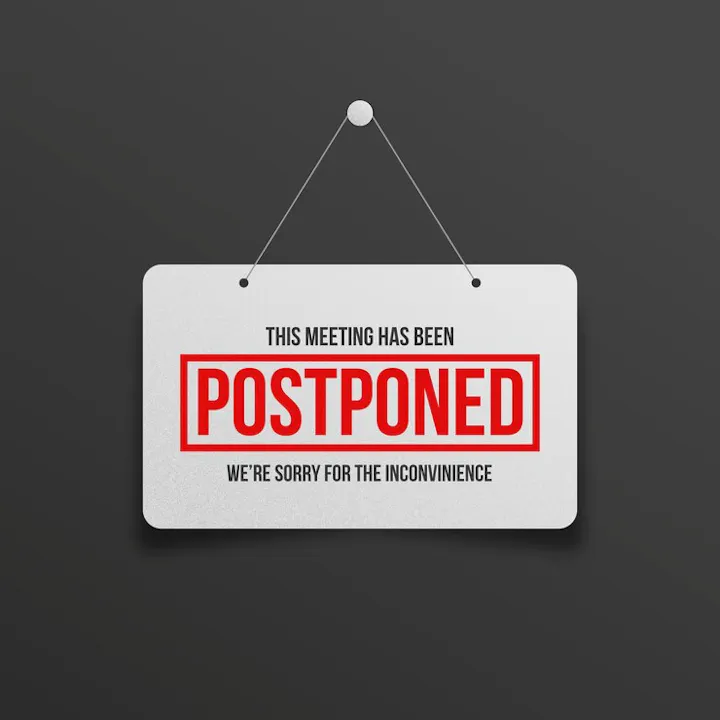 Sign hanging on a wall saying "This meeting has been POSTPONED - We're sorry for the inconvenience."