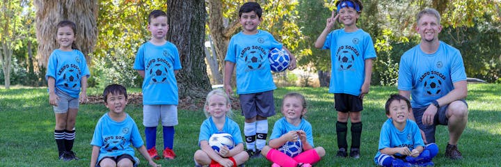 A youth soccer team posing with their coach in matching blue uniforms.