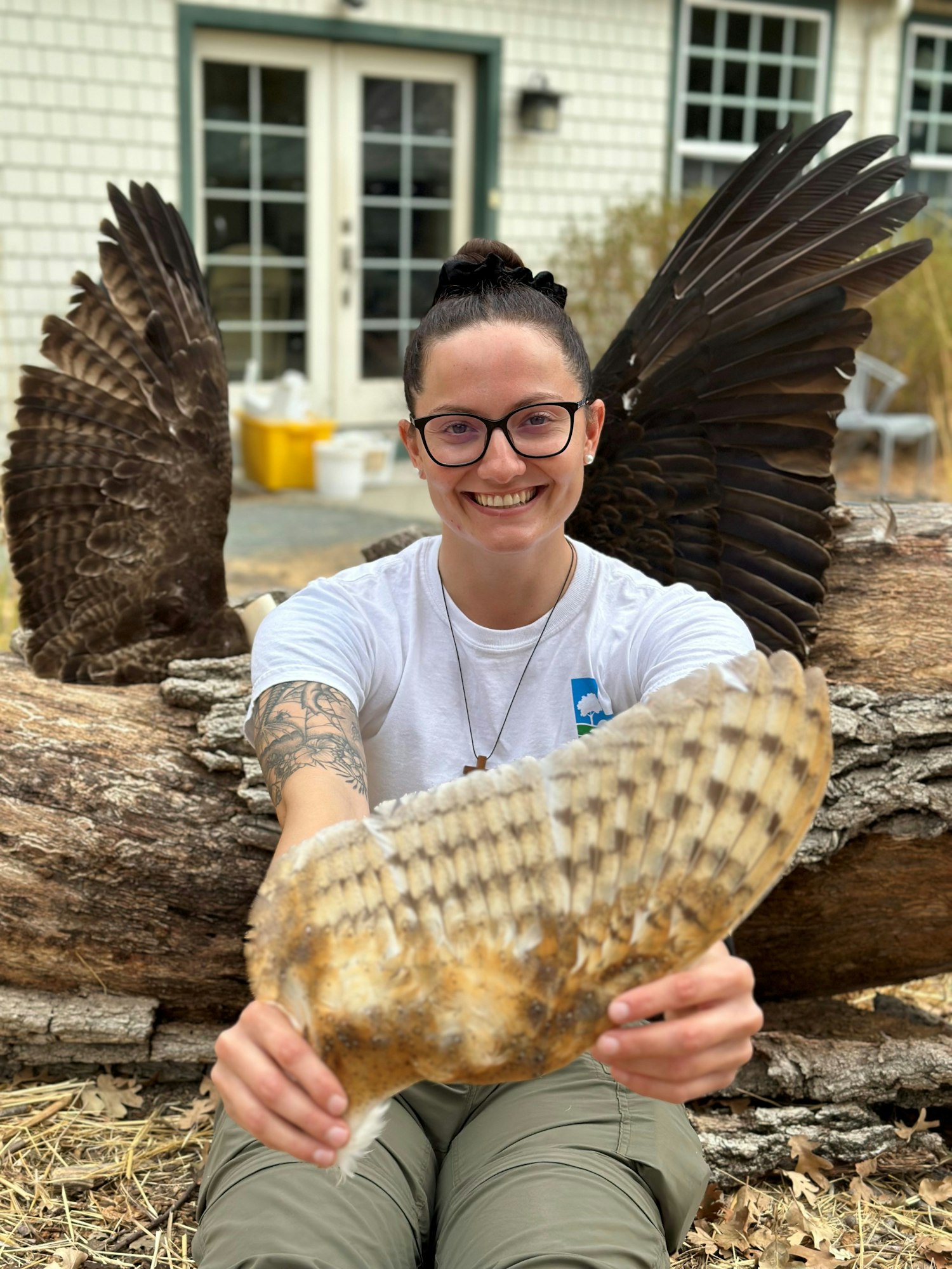 May contain: face, head, person, photography, portrait, accessories, glasses, animal, beak, bird, clothing, t-shirt, pants, wood, body part, finger, hand, rock, jewelry, necklace, skin, and tattoo