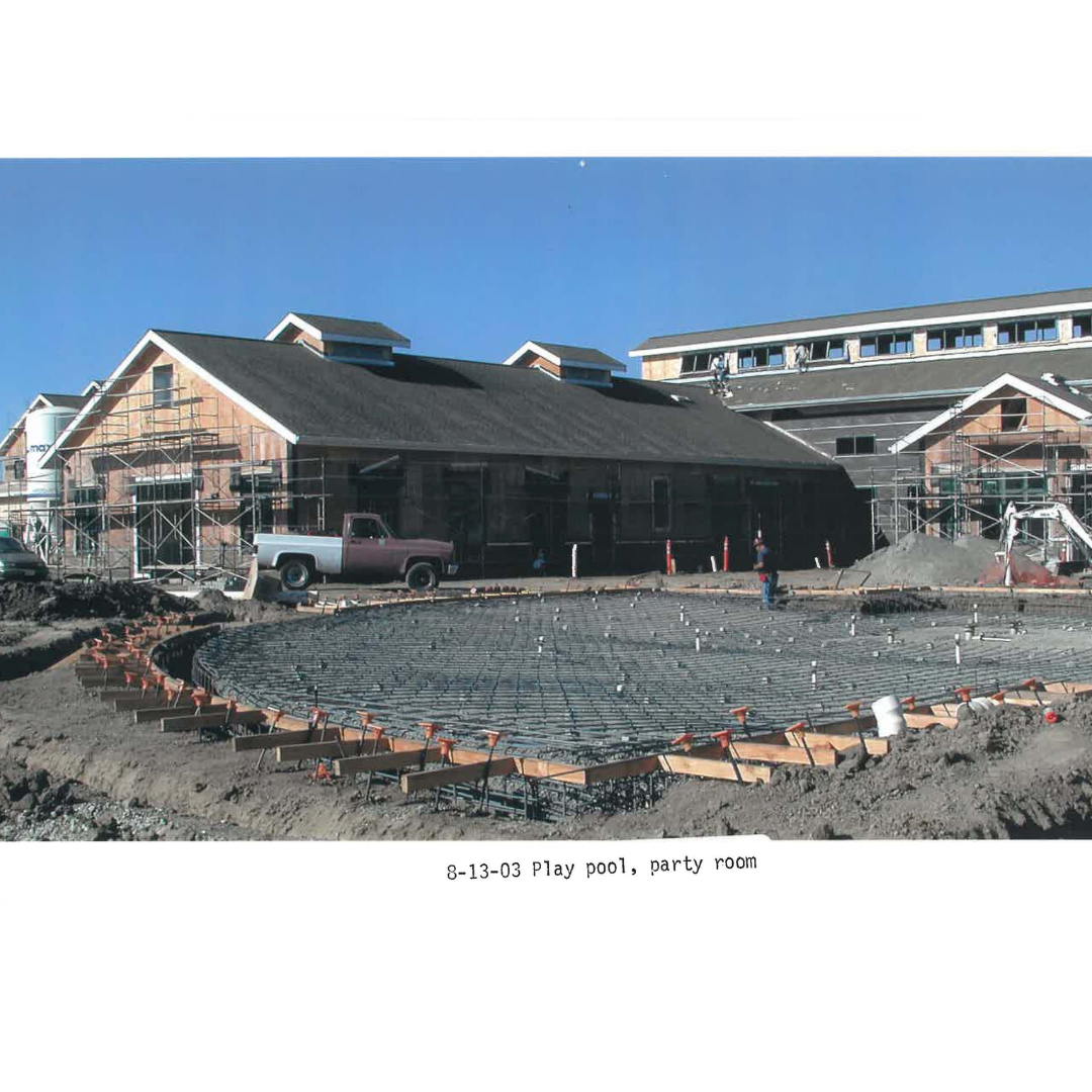 Construction site with building, scaffolding, truck, and circular foundation work labeled "8-13-03 Play pool, party room".