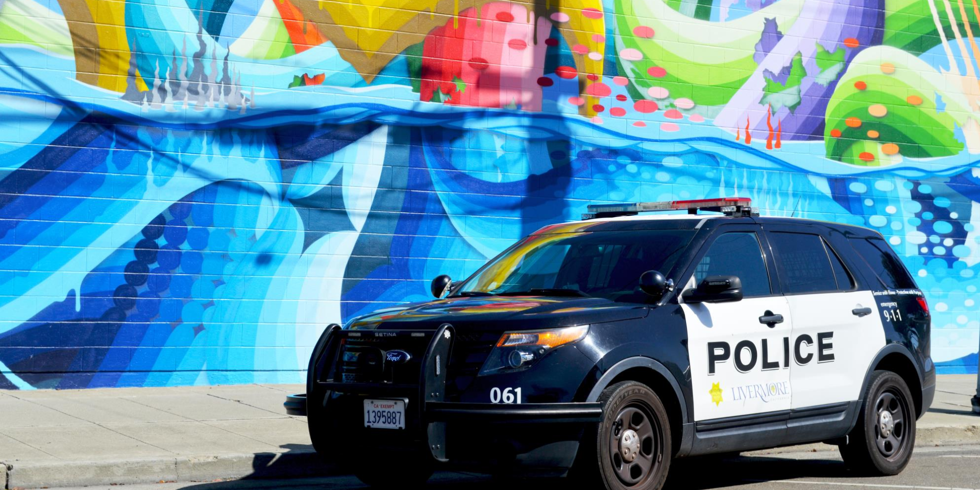 Police car parked beside a colorful mural.