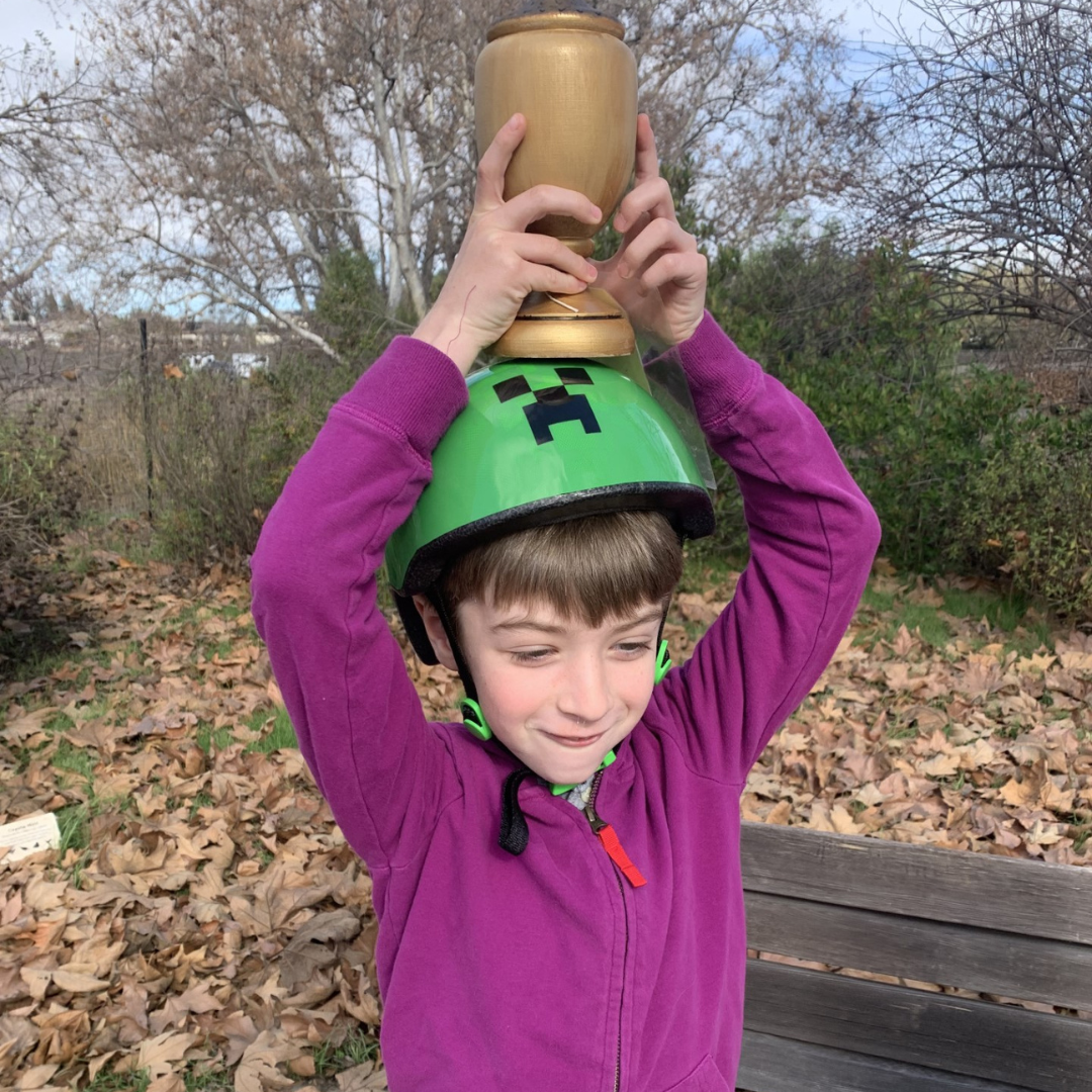 May contain: face, head, person, photography, portrait, pottery, plant, vegetation, grass, nature, outdoors, park, jar, helmet, clothing, coat, jacket, soil, herbal, herbs, and tree