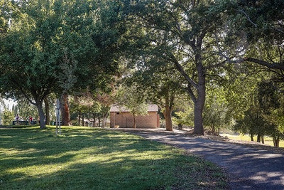 A park path with trees and a small building in the background under a clear sky.