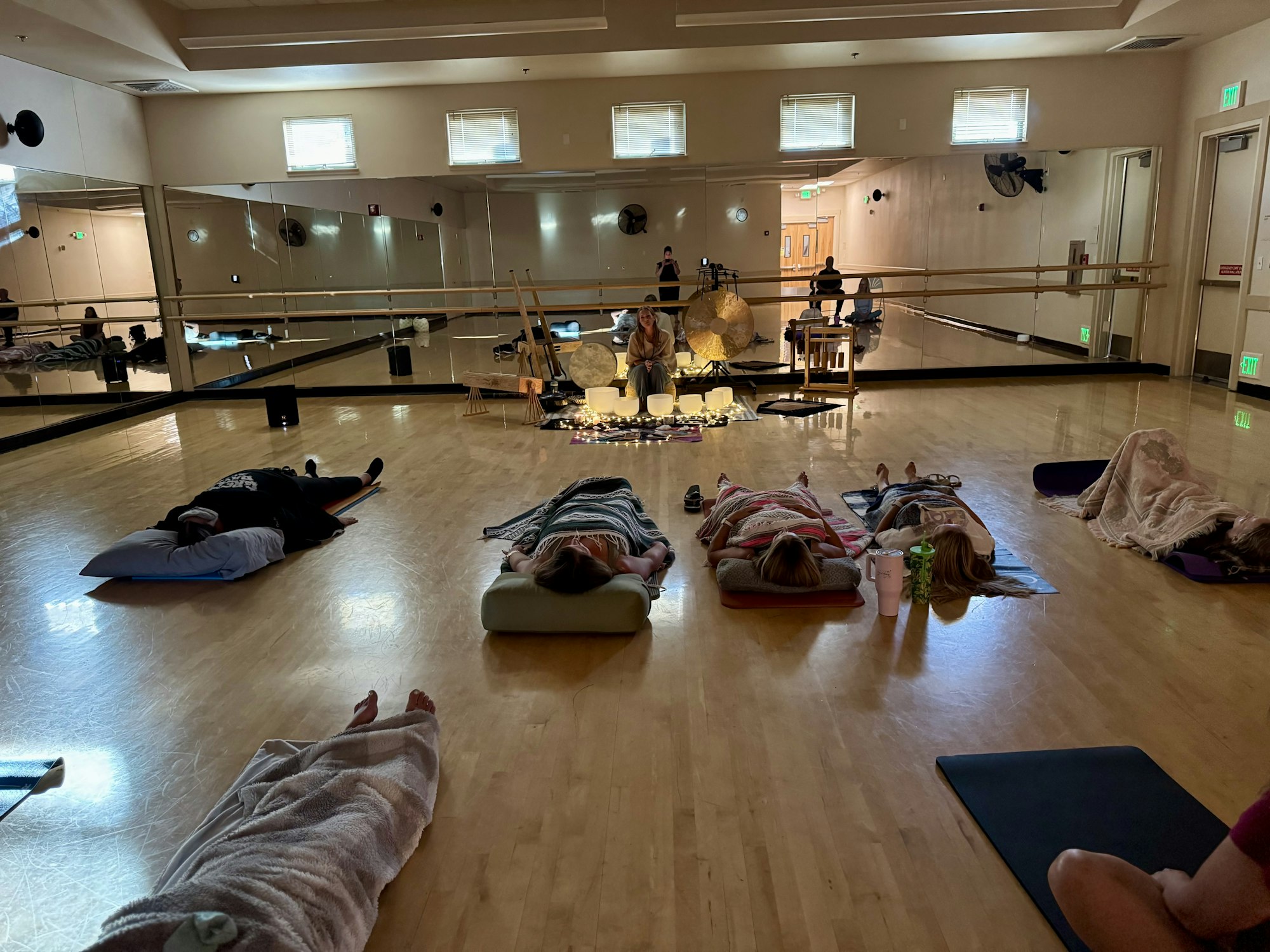 A group relaxation session on yoga mats in a studio with dim lighting and sound equipment.