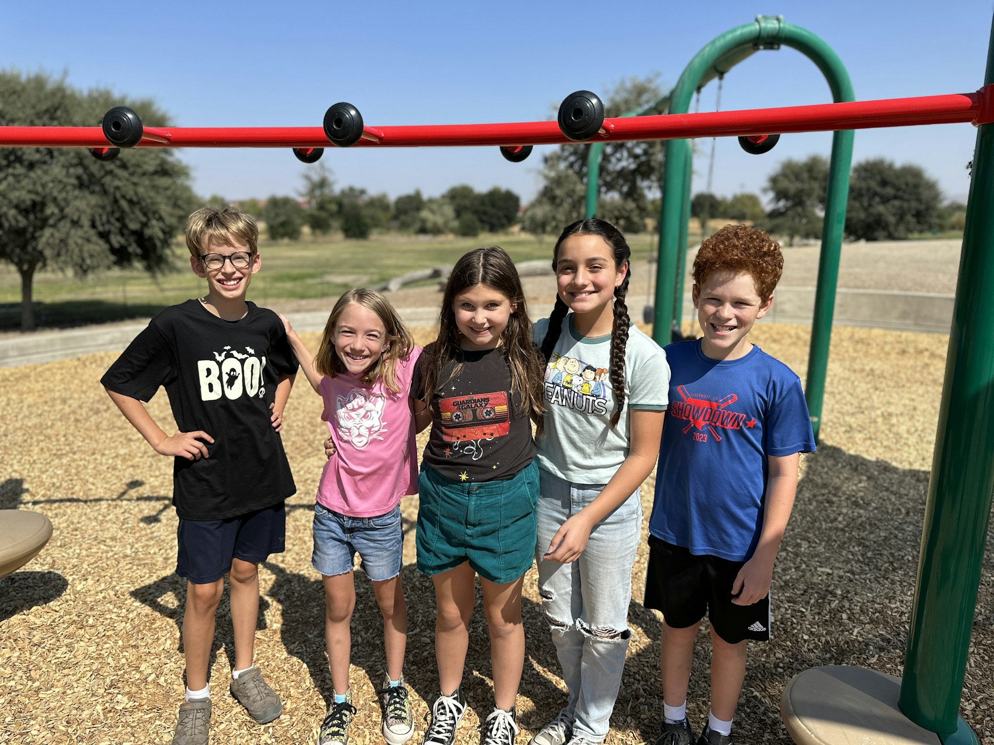 May contain: grass, nature, outdoors, park, plant, female, girl, person, teen, clothing, t-shirt, shorts, footwear, shoe, play area, face, head, photography, portrait, boy, male, outdoor play area, pants, child, accessories, glasses, and people