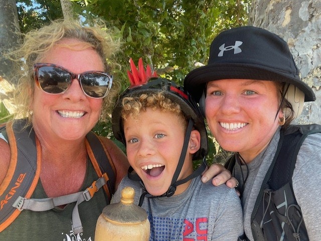 Three people smiling for a selfie, two women and a child with a bike helmet.
