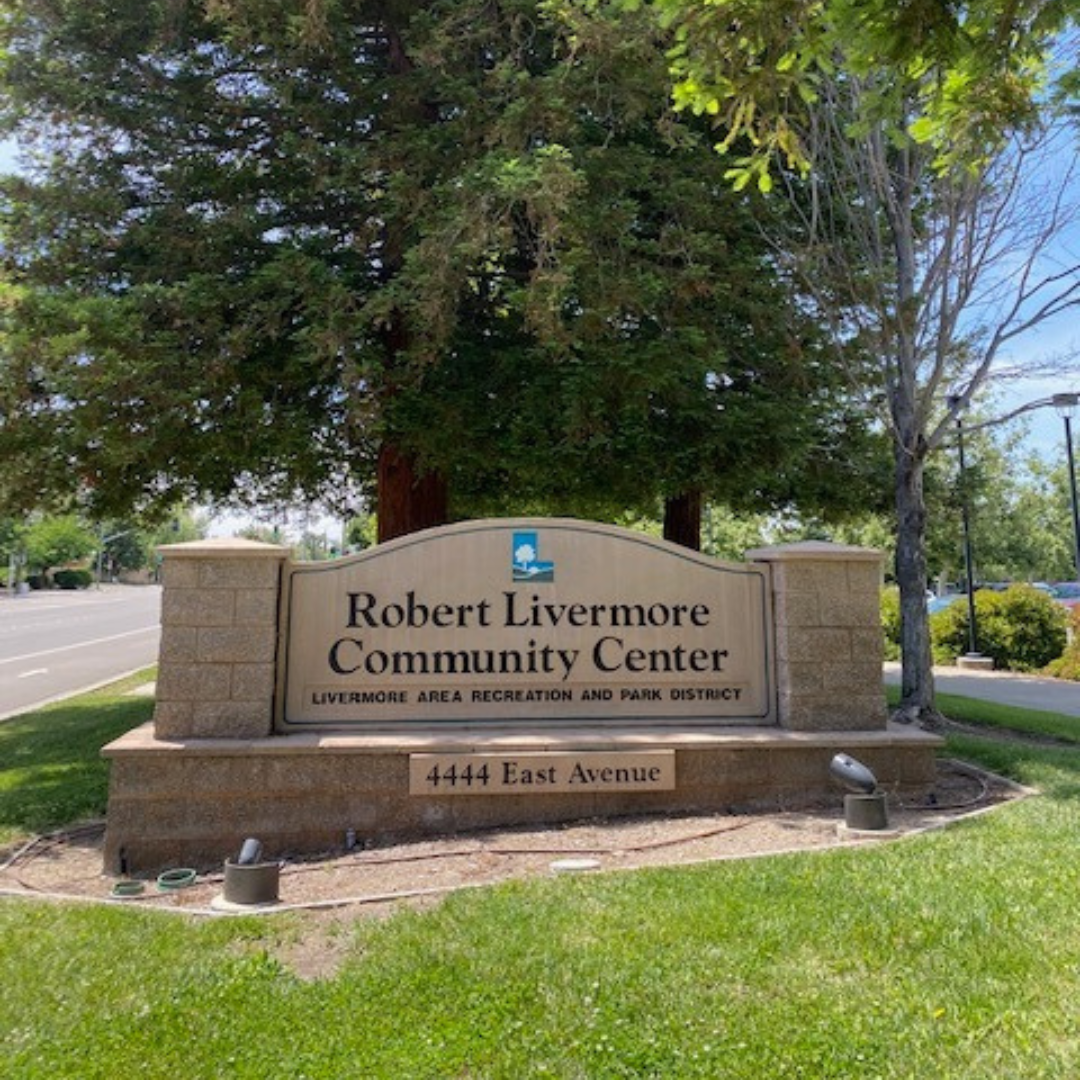 Sign for Robert Livermore Community Center on 4444 East Avenue, set in a greenery-filled area.