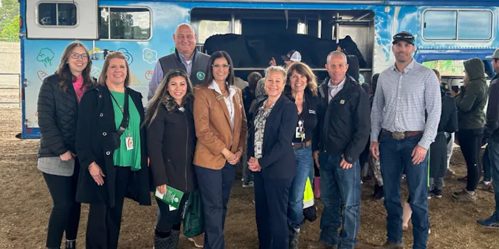 A group of people posing for a photo in front of a blue truck, likely at an event related to agriculture or education.