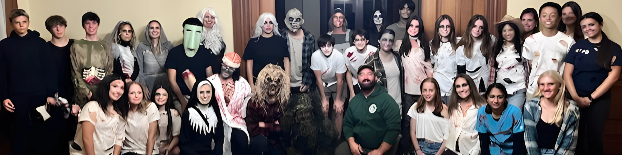 A group of people in various Halloween costumes, posing indoors.