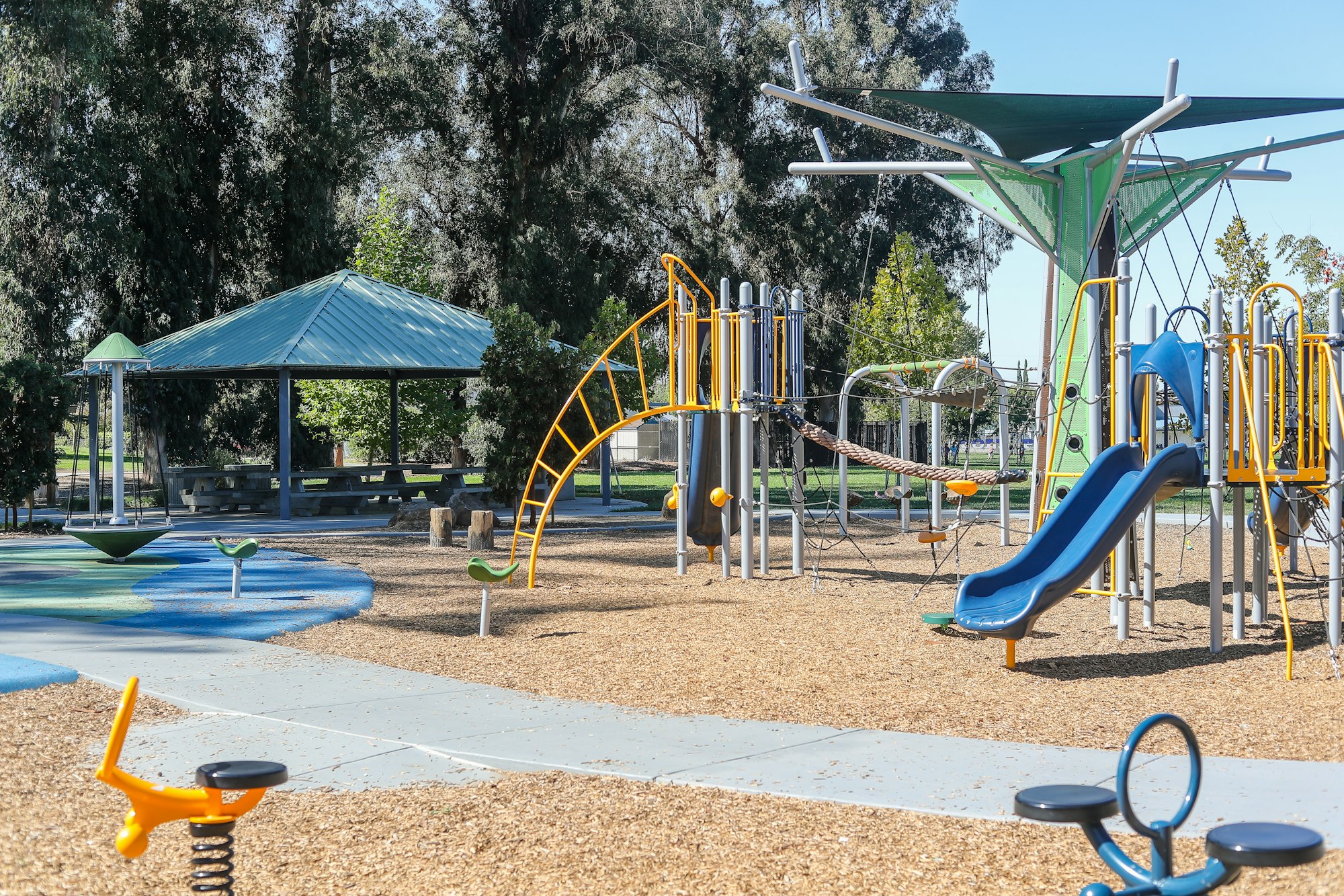 Playground with slides, swings, and climbing structures on a sunny day.