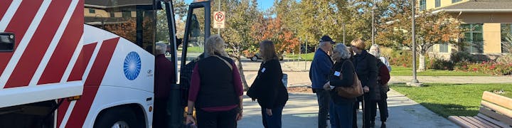 People are queuing to board a bus parked at a loading zone.