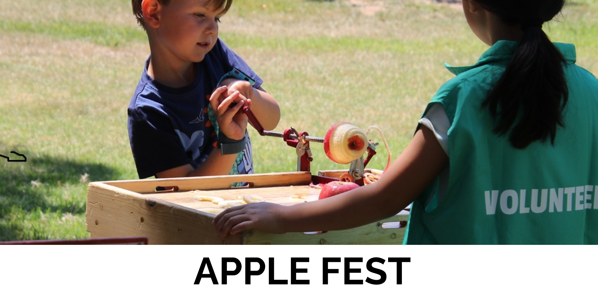 A child is peeling apples at an outdoor event called "Apple Fest," assisted by a volunteer in a green vest.