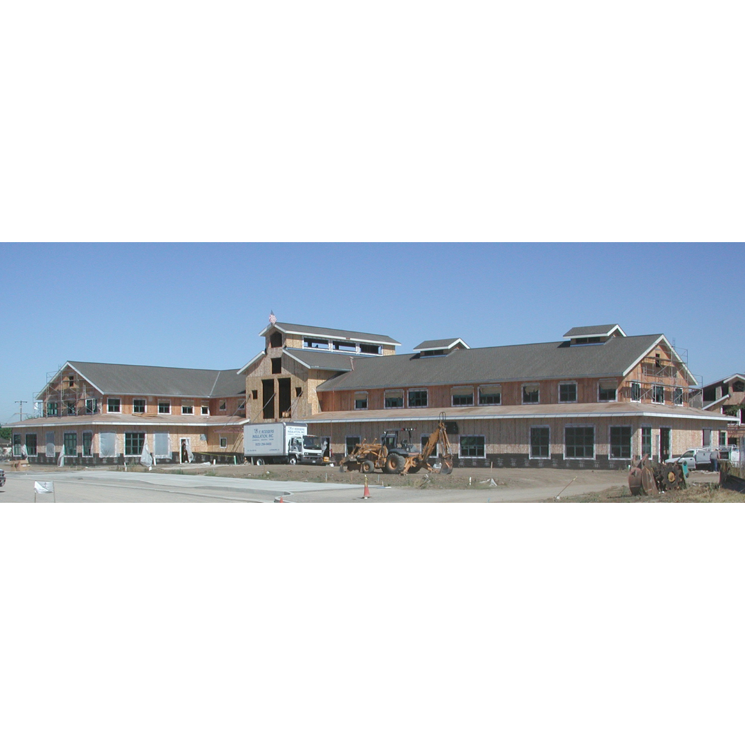 Large building under construction with vehicles and equipment at the site.