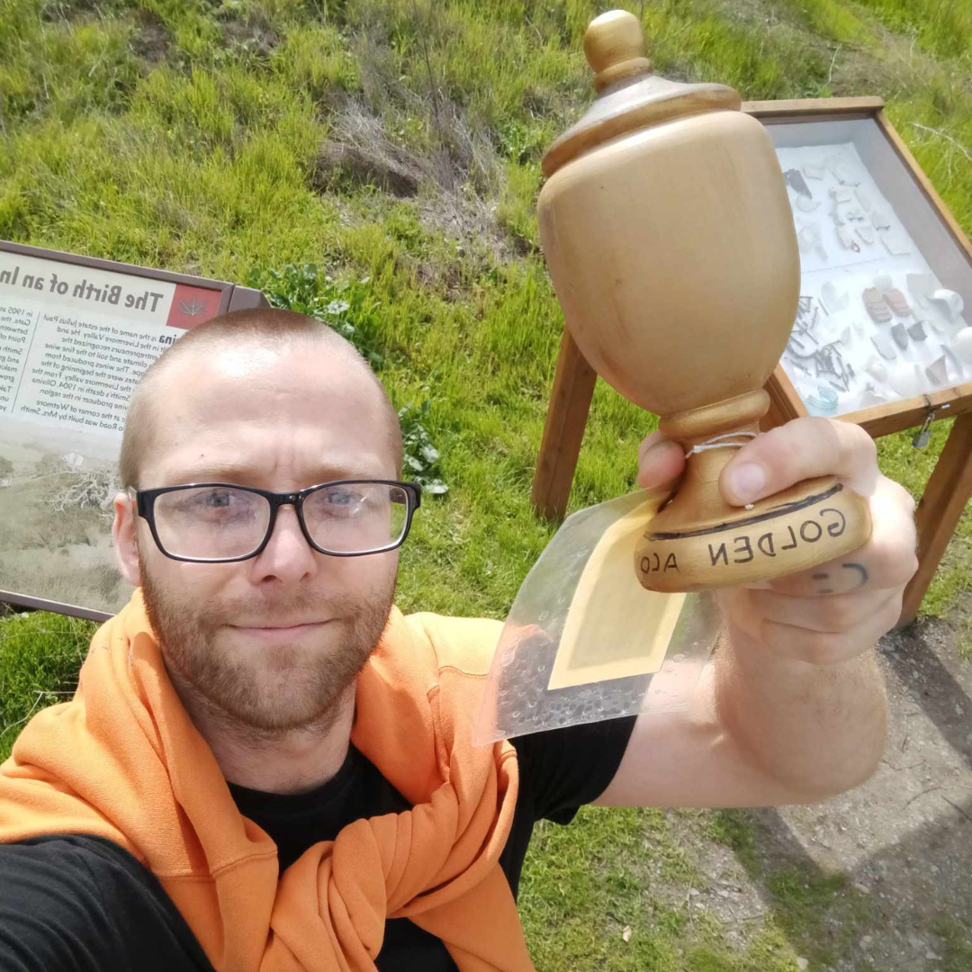 A person taking a selfie holding a trophy upside down.