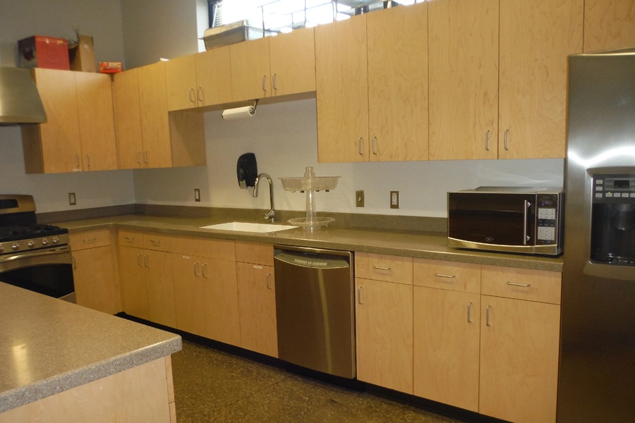 A kitchen with wooden cabinets, countertop, stove, dishwasher, microwave, and coffee maker.