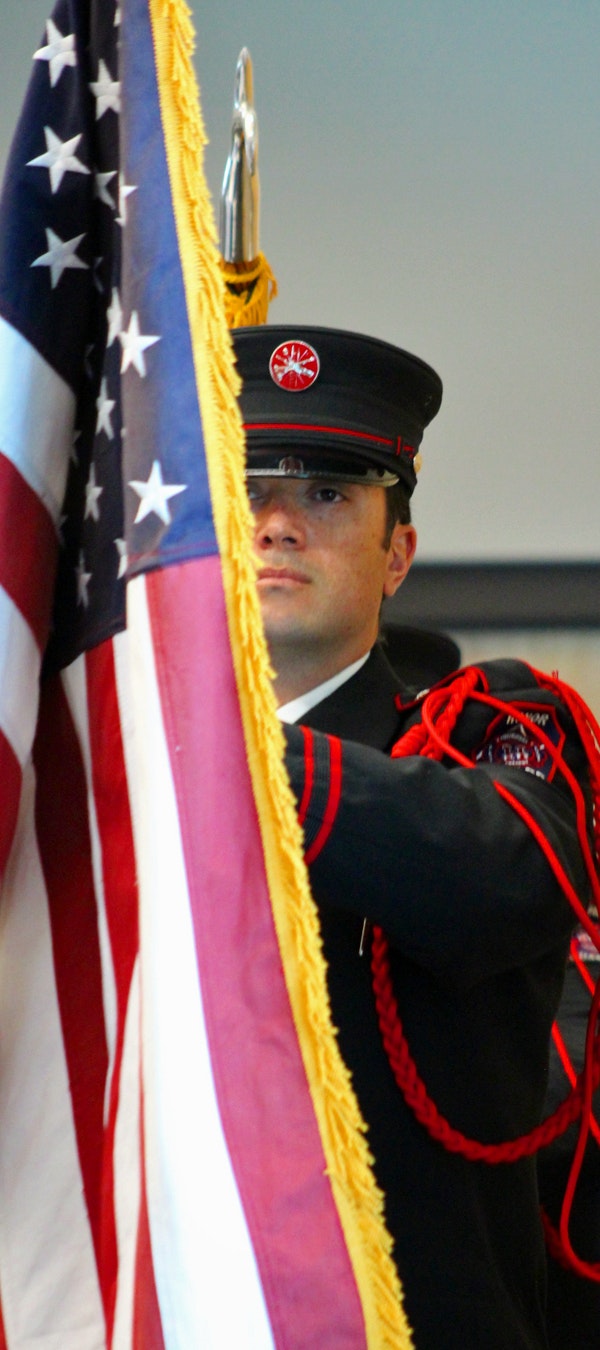 A person in uniform with an American flag, possibly part of a ceremonial event.